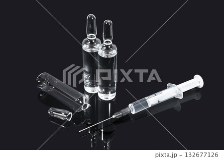 Ampoules with transparent vaccine and syringe on dark background Ampoules with transparent vaccine and syringe on dark background 132677126