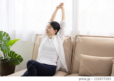 ソファで伸びをするミドル女性 132677265
