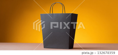 A black paper bag with handles on a yellow background A black paper bag with handles on a yellow background 132678359