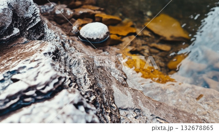 Rocky shoreline with calm water and shells at midday 132678865