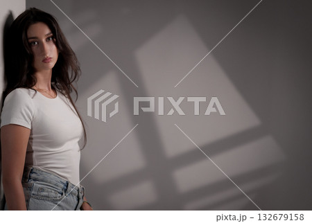 Fashion model posing near wall with window shadows Fashion model posing near wall with window shadows 132679158