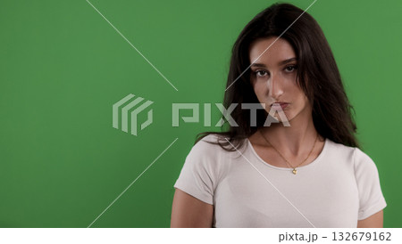 Fashion model posing with a serious expression on green background 132679162