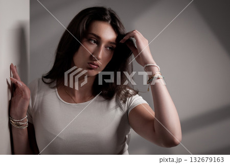 Fashion model posing and touching her hair in studio with white background 132679163