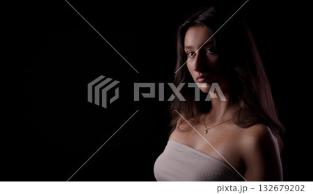 Fashion model posing with strapless top and necklace on black background Fashion model posing with strapless top and necklace on black background 132679202