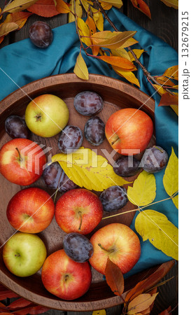 Autumn Fruit Arrangement With Apples, Plums, Leaves On Wooden Tray Over Blue Cloth 132679215