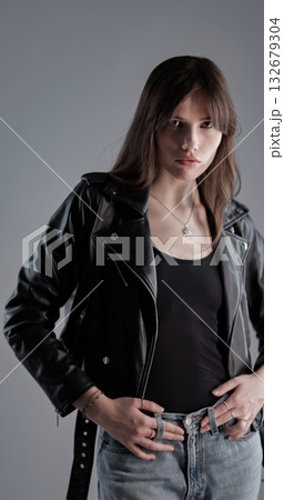 Fashion model posing with black leather jacket and jeans 132679304