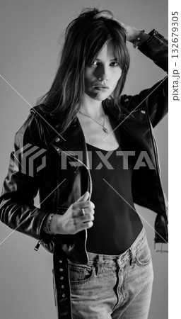 Fashion model wearing leather jacket and jeans posing in studio 132679305