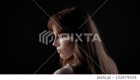 Fashion model posing with long brown hair on black background Fashion model posing with long brown hair on black background 132679326