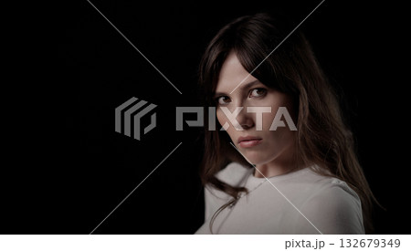 Fashion model posing with serious expression on black background Fashion model posing with serious expression on black background 132679349