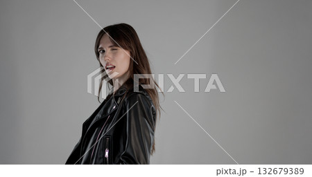 Fashion model winking and sticking out tongue wearing black leather jacket 132679389