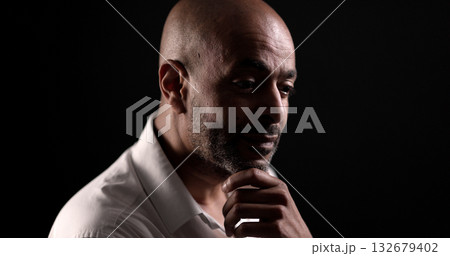 Pensive African American businessman touching his chin in dark room 132679402