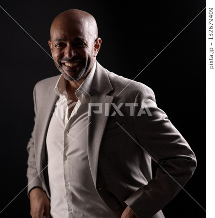 Smiling african american businessman posing with hands in pockets on black background 132679409