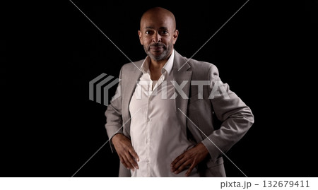 Confident African American businessman posing with hands on hips on black background 132679411