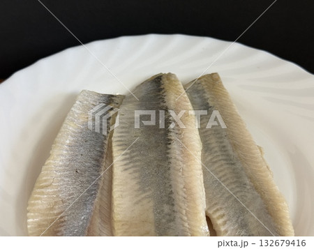 Close-up of a lightly salted herring fillet on a white plate. Healthy, natural food. 132679416