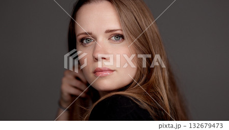 Beautiful woman playing with her hair on gray background Beautiful woman playing with her hair on gray background 132679473