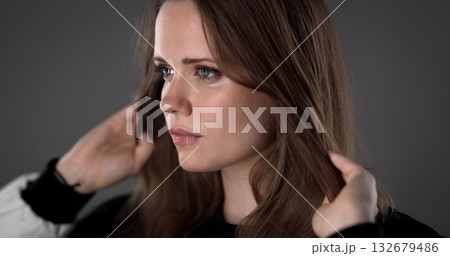 Beautiful young woman playing with her hair on gray background 132679486