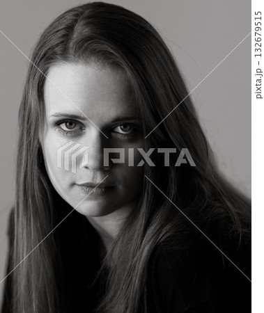 Serious young woman with long brown hair posing in black and white 132679515