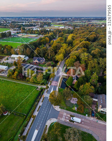 Aerial view of suburban landscape central road, houses, sports fields, canal, and forested zone with autumn foliage, blending residential planning 132679565