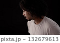 Young african-american man with curly hair looking away and talking on black background 132679613