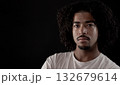 Serious young african-american man with curly hair posing on black background 132679614