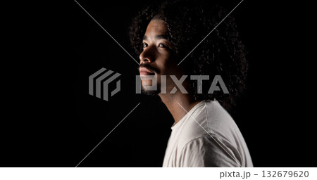 Young african-american man with curly hair looking up on black background 132679620