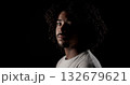 Young african-american man with curly hair posing in studio with black background 132679621