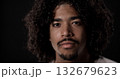 Portrait of a serious young african-american man with curly hair and goatee looking intensely against a black background 132679623