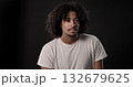 Young african-american man with curly hair posing on dark background 132679625