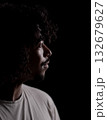 Young african-american man with curly hair looking hopeful in profile on black background 132679627