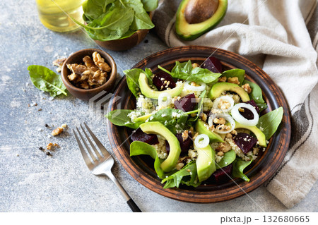 Couscous with avocado, beet, fresh spinach and dressing vinaigrette on a grey stone background. Healthy natural plant based vegetarian food, low calories dieting meal. Copy space. Couscous with avocado, beet, fresh spinach and dressing vinaigrette on a grey stone background. Healthy natural plant based vegetarian food, low calories dieting meal. Copy space. 132680665