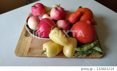 A wooden board with a variety of fruits and vegetables on it. 132681214