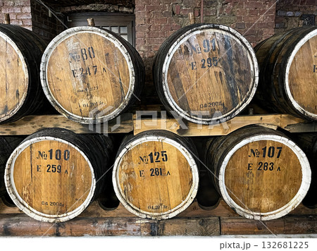 A brick oven sits in front of a row of barrels. 132681225
