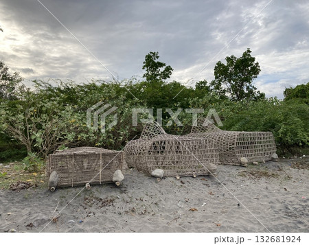 Trap for crab fish lobster lobsters cages braided from bamboo lie on a sandy shore Trap for crab fish lobster lobsters cages braided from bamboo lie on a sandy shore 132681924