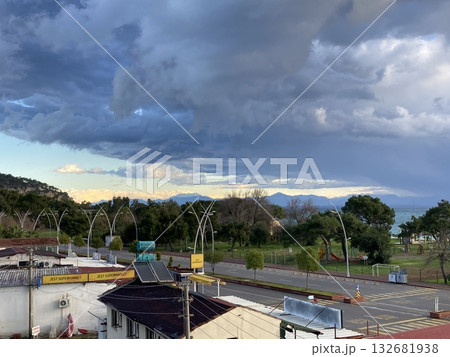 View from the roof of the house to the roofs of houses to the sea, mountains and park, thick low clouds 132681938