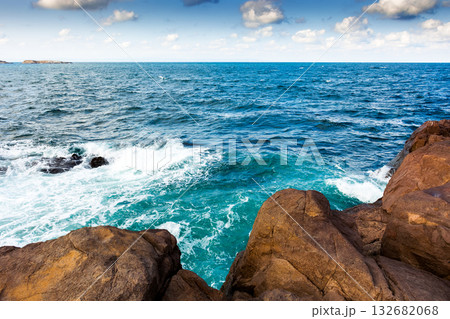 waves crashing rocky beach at the sea on a sunny evening. beautiful coast background with blue sky and fluffy clouds in afternoon light. travel destination at the bulgarian seaside. recreation concept 132682068