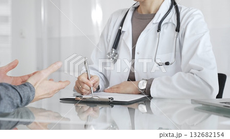Doctor consulting patient, physician writing medical notes during healthcare examination in modern clinic office. Medicine and health care Doctor consulting patient, physician writing medical notes during healthcare examination in modern clinic office. Medicine and health care 132682154