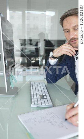 Businessman in a blue jacket thinking and brainstorming ideas while working on computer and taking notes in modern office. Business people concept 132682187