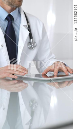 Doctor using tablet computer, providing healthcare consultation, digital medical technology, professional man in lab coat. Medicine and health care 132682191