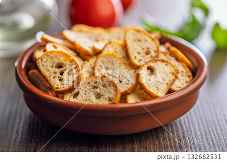 Crispy roasted bruschetta bread in bowl on wooden table. 132682531