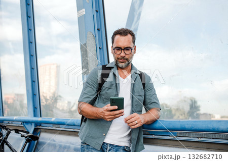 Bearded man using phone while waiting for bus. 132682710