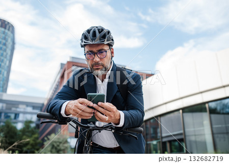 City commuter riding bike from work, reading text message on phone. City commuter riding bike from work, reading text message on phone. 132682719