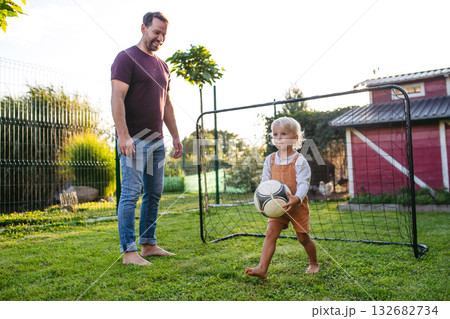 Little boy playing football with father in backyard. Little boy playing football with father in backyard. 132682734