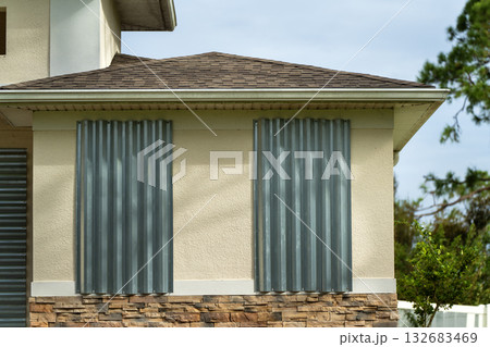 Hurricane shutters made from steel mounted for protection of house windows. Protective measures before natural disaster in Florida Hurricane shutters made from steel mounted for protection of house windows. Protective measures before natural disaster in Florida 132683469