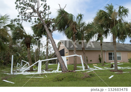 Hurricane damage to white PVC backyard fence ruined after tree debris fell down on it in Florida 132683478