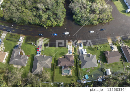 Flooded Florida road with evacuating cars and surrounded with water houses in suburban residential area. Consequences of hurricane natural disaster Flooded Florida road with evacuating cars and surrounded with water houses in suburban residential area. Consequences of hurricane natural disaster 132683564