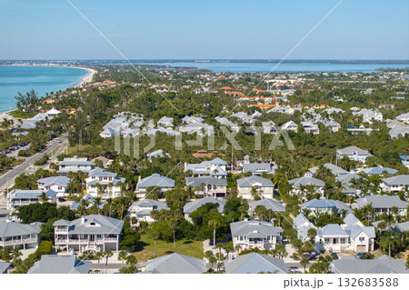 Expensive mansions between green palm trees on Gulf of Mexico shore in island small town Boca Grande on Gasparilla Island in southwest Florida, USA. Aerial view of wealthy waterfront neighborhood Expensive mansions between green palm trees on Gulf of Mexico shore in island small town Boca Grande on Gasparilla Island in southwest Florida, USA. Aerial view of wealthy waterfront neighborhood 132683588