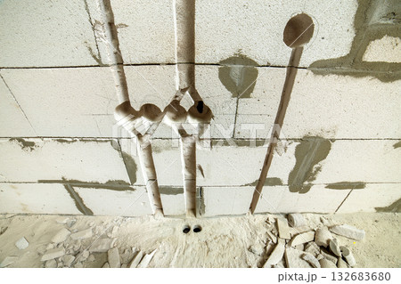 Deep grooves and holes in white brick wall made for installation of electrical cables. Deep grooves and holes in white brick wall made for installation of electrical cables. 132683680