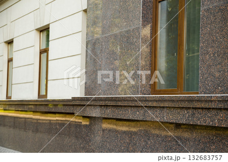 Close up view of part of a building facade with the surface of granite wall. Natural stone materials. 132683757