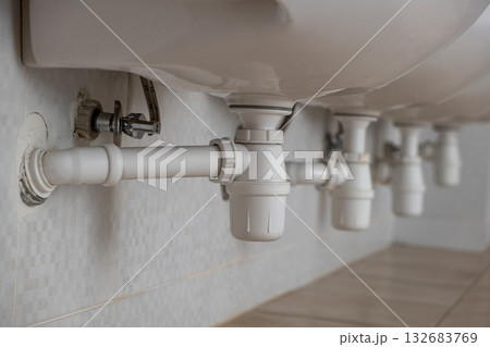 Close up of white plastic pipe drain under washing sink in bathroom. 132683769
