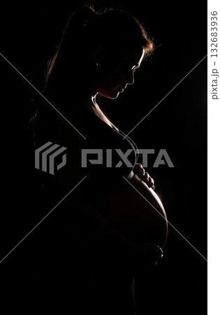 Pregnant woman embracing her belly in silhouette 132683936